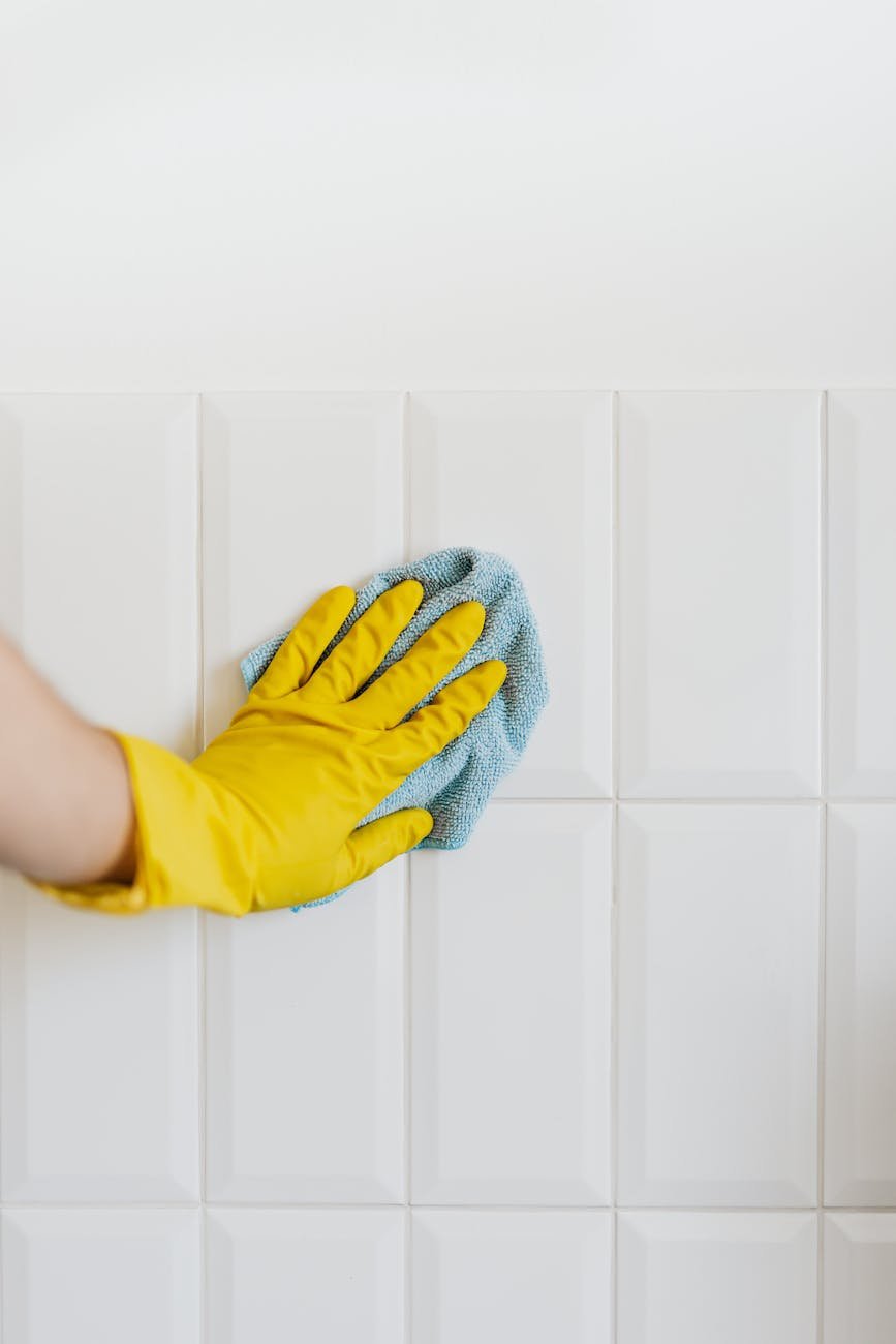 Professional post-construction cleanup team using microfiber cloths and ladders to remove dust from ventilation and high surfaces
